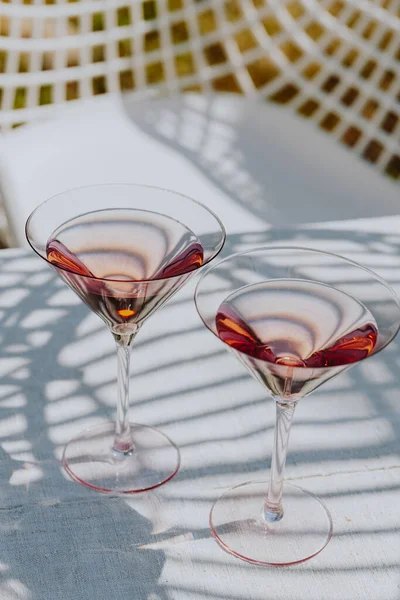 Two glasses with cold pink rose on a garden table in the summer sun. High quality photo