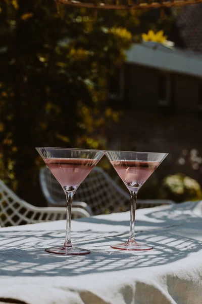 Two glasses with cold pink rose on a garden table in the summer sun. High quality photo