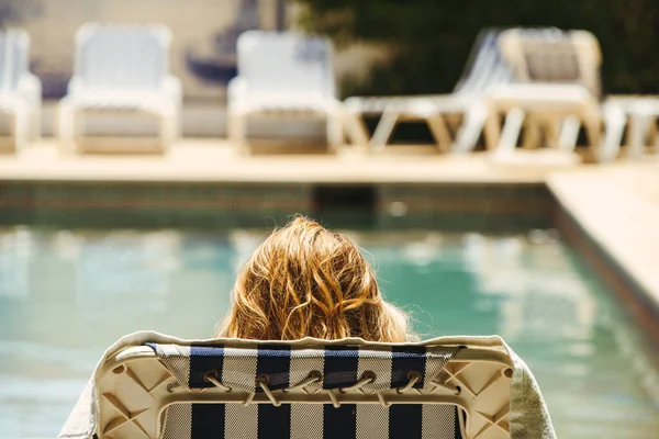 Girl relaxing in a sun-bed at a pool. . High quality photo