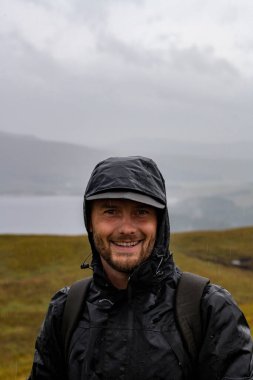 Kameraya gülümseyen mutlu yürüyüşçü. Ormanda yağmur. Sırt çantası. Yüksek kalite fotoğraf