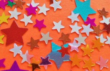 Turuncu arka planda yıldız şeklinde konfetiden yapılmış doğum günü kartpostalı