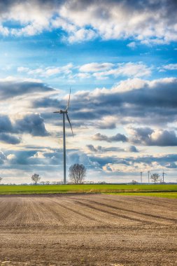 Mavi gökyüzü ve turbo jeneratörle elektrik rüzgar türbini üretiliyor.