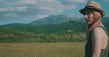 Güneşli dağ çayırlarında şapkalı bir kadının portresi..