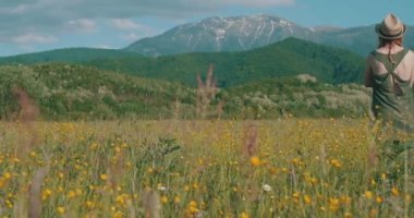Güneşli bir dağ yaban çiçeği tarlasında bir kadın.