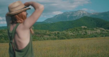 Şapkalı kadın dağlara doğru bakıyor..