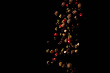 Siyah arka planda uçuşan çok renkli parlak baharatlar ve biberler. Yüksek kalite fotoğraf