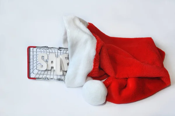 Beyaz arkaplanda, Noel Baba şapkasında alışveriş torbası satışı yazıyor. Noel indirimi kavramı, beyaz arka planda Xmas pazarı hediyesi. Seçici odak
