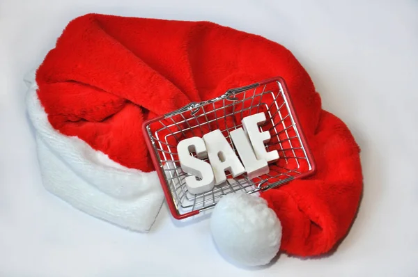 Beyaz arkaplanda, Noel Baba şapkasında alışveriş torbası satışı yazıyor. Noel indirimi kavramı, beyaz arka planda Xmas pazarı hediyesi. Seçici odak
