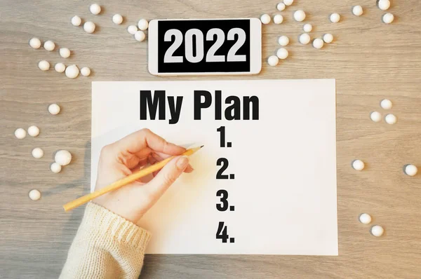 Planım - beyaz telefon 2022 ile deftere yazmak, yeni yıl karar planı konsepti. Yeni iş yılı başlıyor..