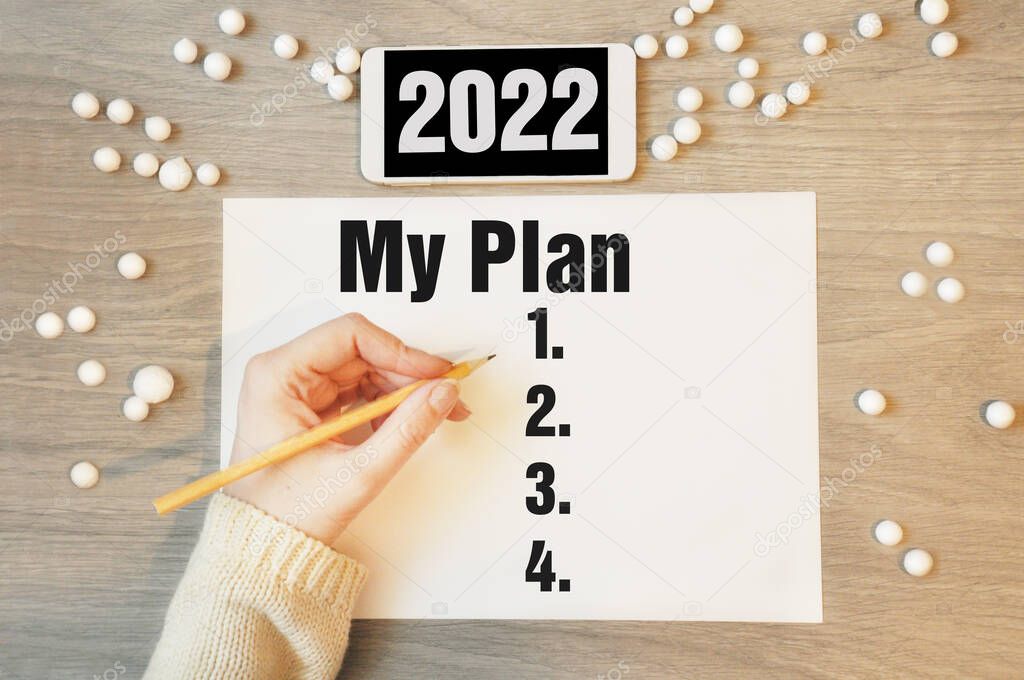 My plan - writing in notebook with white phone 2022, concept for new year resolutions plan. Beginning new bussiness year.