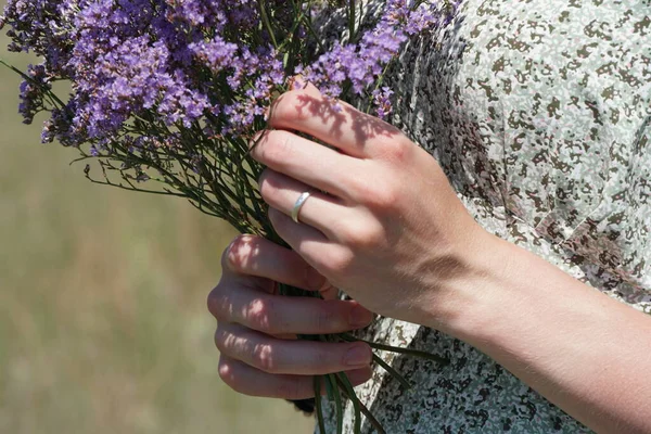 hands of female hand holding a flower in her arm, in the park, in a summer garden,