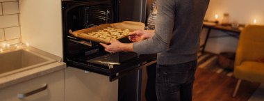 Bir çocuk kurabiye tepsisini fırına koyar.