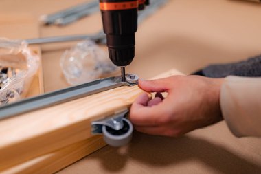 Adam yeni bir yatak kurulumunda çalışıyor ve kablosuz matkap kullanıyor.