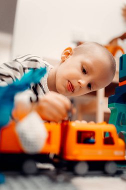 Evde oyuncak tren yolunda plastik trenle oynayan mutlu bir çocuk..