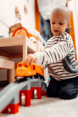 Evde oyuncak tren yolunda plastik trenle oynayan mutlu bir çocuk..