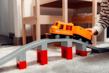 Evde oyuncak tren yolunda plastik trenle oynayan mutlu bir çocuk..