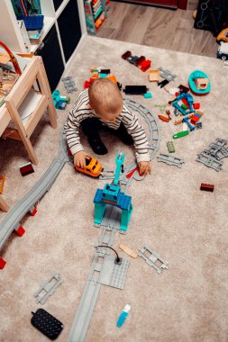 Halı zemininde oyuncak tuğlalarla oynayan mutlu anaokulu çocuğu. çocukluk eğitimi yapı kavramı