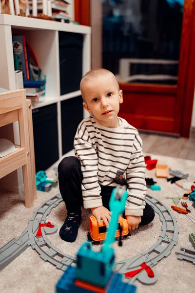 Halı zemininde oyuncak tuğlalarla oynayan mutlu anaokulu çocuğu. çocukluk eğitimi yapı kavramı