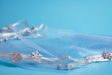 Mavi arka planda Noel süsü. Kumaşın üzerinde gümüş kurdele ve gümüş boncuklar var. Seçici odaklanma, yakın plan. Kopyalanacak bir yer.