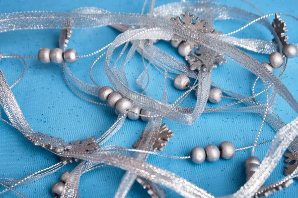Decorazione natalizia su sfondo blu. Nastro d'argento e perline d'argento si trovano sul tessuto. Concentrazione selettiva, primo piano. Un posto da copiare. — Foto Stock