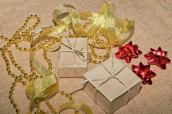 Weihnachtsdosen aus Bastelpapier liegen auf dem Tisch, dekoriert mit Goldbändern und Perlen. Weihnachtlicher Hintergrund. Feierlicher Hintergrund. Blick von oben. — Stockfoto