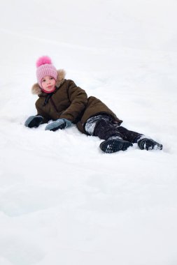 Mutlu, gülümseyen komik bir çocuk, kışın dışarıda yürüyen, karla oynayan bir kız. Güneşli bir kış günü.