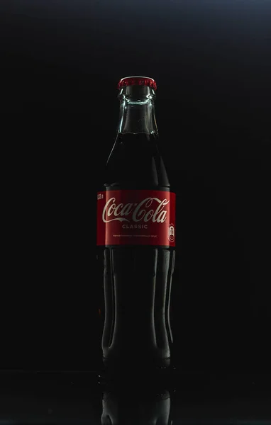 Siyah arka planda cam Coca-Cola şişesi.