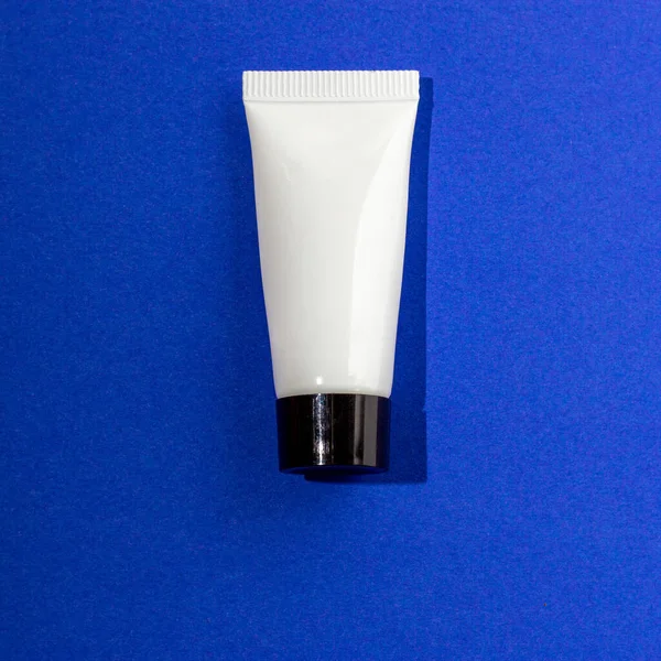 Mavi arka planda beyaz krem tüpü 