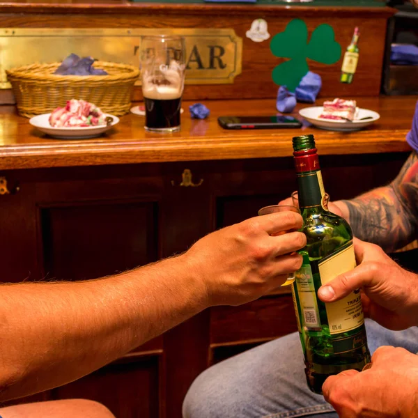 Bardaki müşterilerin elinde alkol var.