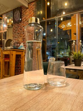 Restorandaki ahşap bir masada yenilenebilir cam su şişesi.