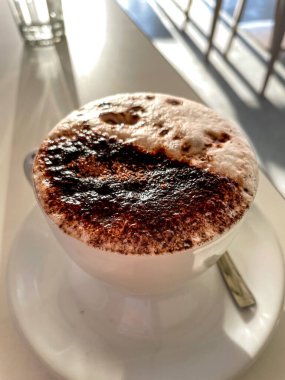 Kafeterya masasında bir fincan sıcak süt ve çikolata