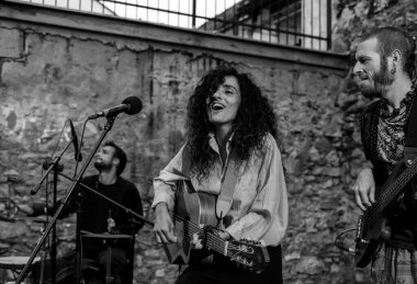 Genç bayan şarkıcı canlı performansta gitar çalıp şarkı söylüyor.