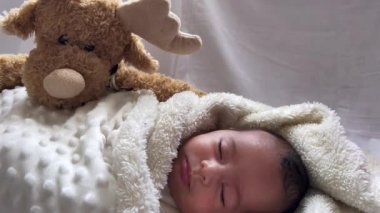 Beyaz bir çarşafın üzerinde uzanmış tatlı, huzurlu bebek gündüz uykusunun tadını çıkar.