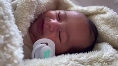Sweet peaceful baby lying on a white bedsheet enjoy daytime nap