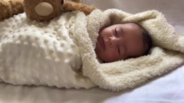 Beyaz bir çarşafın üzerinde uzanmış tatlı, huzurlu bebek gündüz uykusunun tadını çıkar.