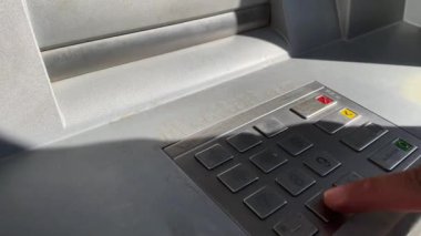 Male's hand pressing the keys of an ATM machine