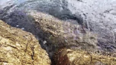 Sahildeki kayalara vuran kısa deniz dalgalarının huzurlu manzarası.