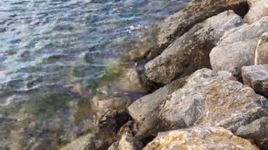 Sahildeki kayalara vuran kısa deniz dalgalarının huzurlu manzarası.