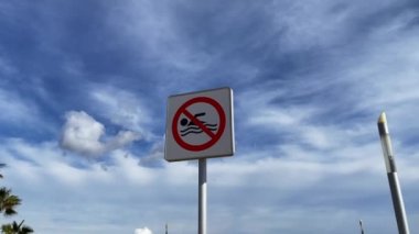 No swimming warning sign with blue sky