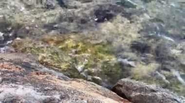 Sahildeki kayalara vuran kısa deniz dalgalarının huzurlu manzarası.