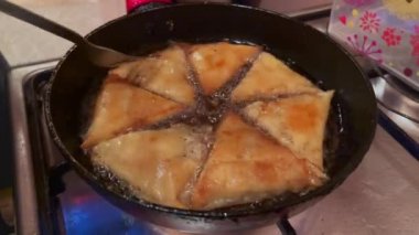 Woman deep frying Briouat at home