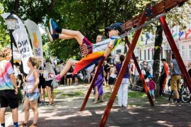 Genç bir çocuk Avrupa 'da bir gurur yürüyüşü sırasında salıncakta oynuyor.