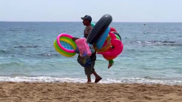Man Walking Beach Selling Inflatable Water Toys — Wideo stockowe