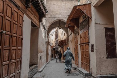 People walking through an empty street in the old Medina of Fes
