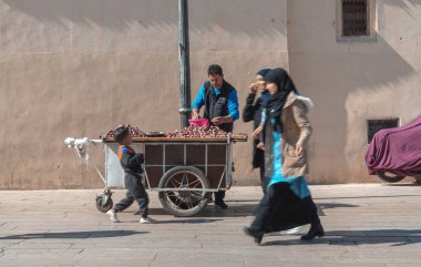 Muslim women walking by a fruit seller in the old Medina of Fez