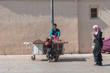 Muslim women walking by a fruit seller in the old Medina of Fez