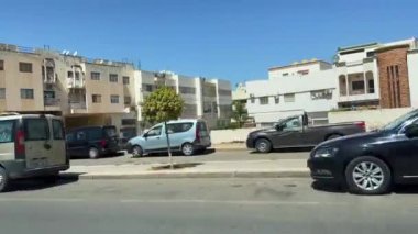 Araba yolda hız yapıyor, caddeyi yan görüyor. 