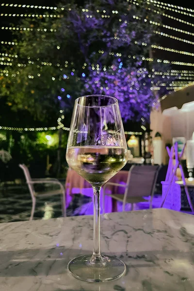 Glass of white wine on a table at night