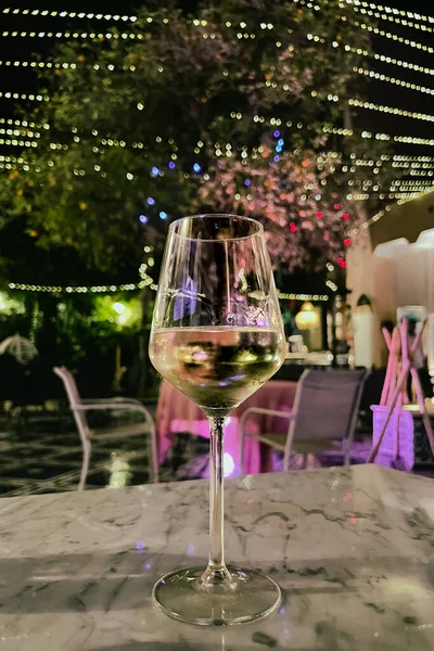 Glass of white wine on a table at night