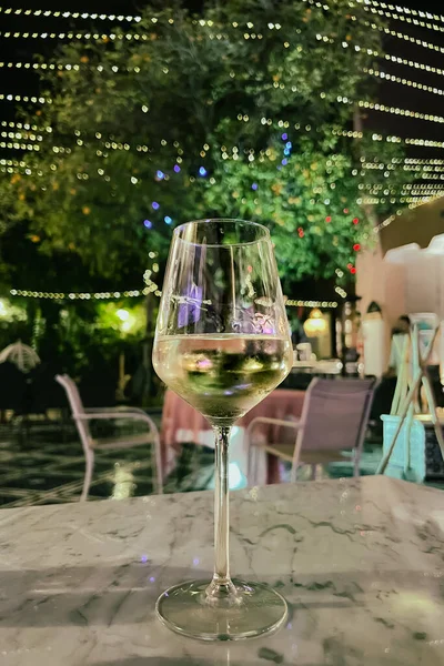 Glass of white wine on a table at night